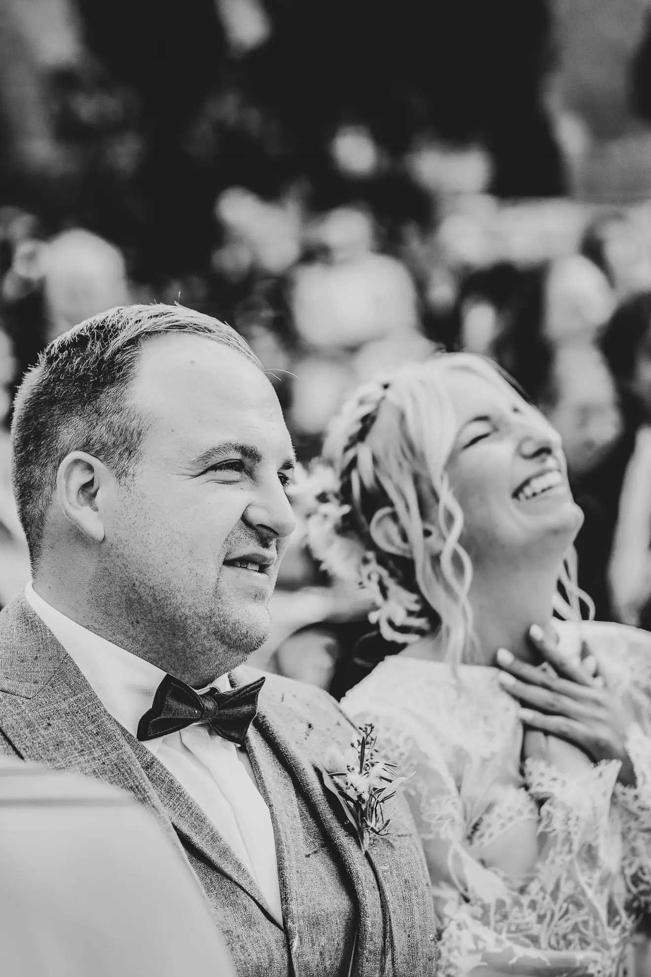 Eine sehr glückliche Braut sitzt neben ihrem Ehemann bei der Trauung und hebt ihre beiden Hände überkreuzt an ihr Herz, während sie von der Hochzeitsfotografin Katja Stumbeck fotografiert wird