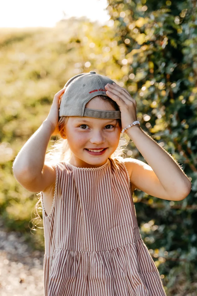 Ein Mädchen hat ein umgedrehtes Baseballcap am Kopf und lächelt in die Kamera