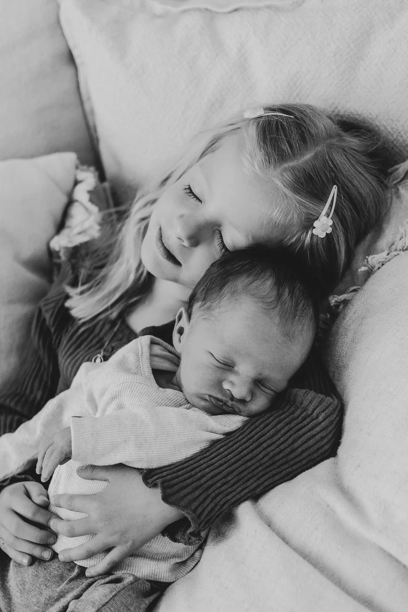 Zwei Geschwister kuscheln miteinander, wobei das eine Kind schon im Kindergartenalter ist und das andere gerade neugeboren wurde im Bayerischen Wald