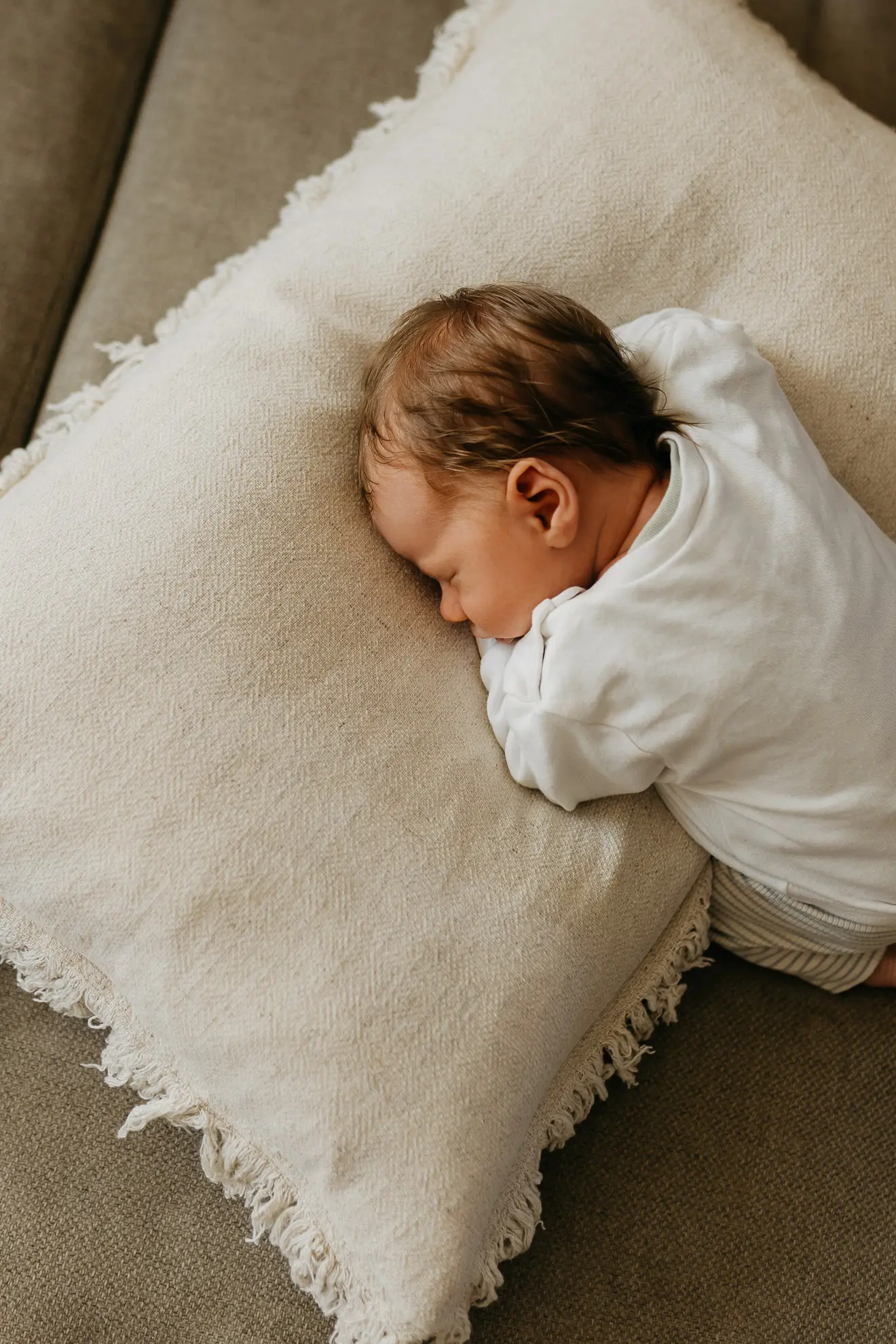 Ein Neugeborenes im Bayerischen Wald hat sich auf ein weißes Kissen gekuscht und wird während dem Schlafen von Fotografin Katja Stumbeck fotografiert