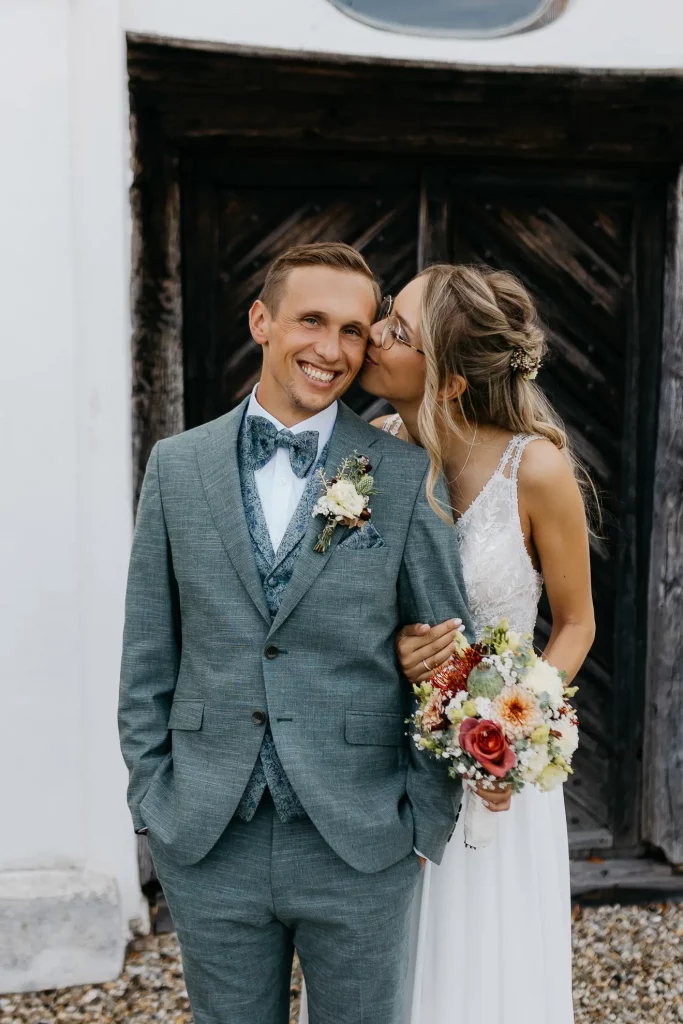 Brautpaar, Braut küsst Bräutigam auf die Wange