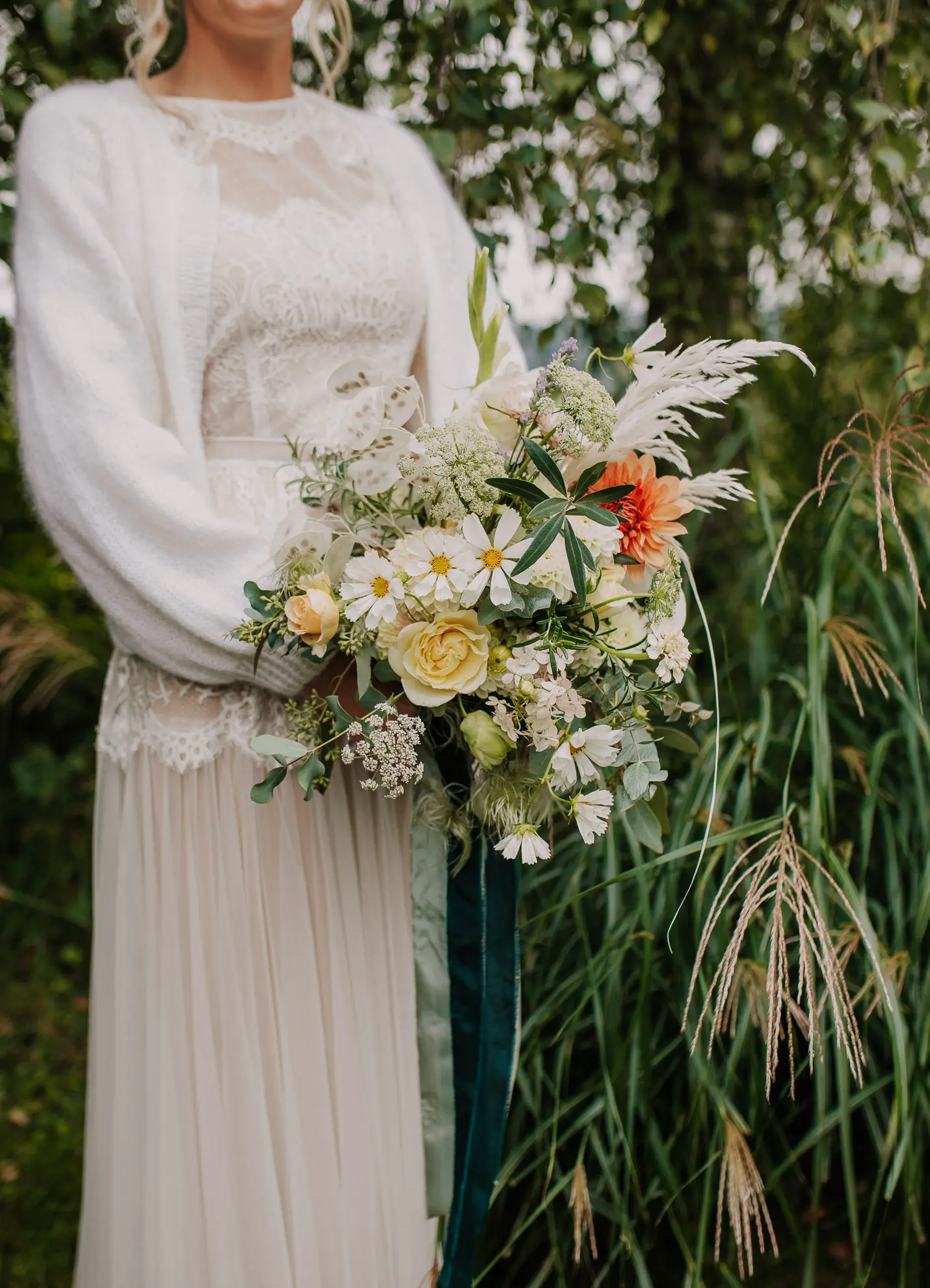 Eine Frau in einem legeren Hochzeitskleid hält einen Blumenstrauß in die Kamera von Hochzeitsfotografin Katja Stumbeck