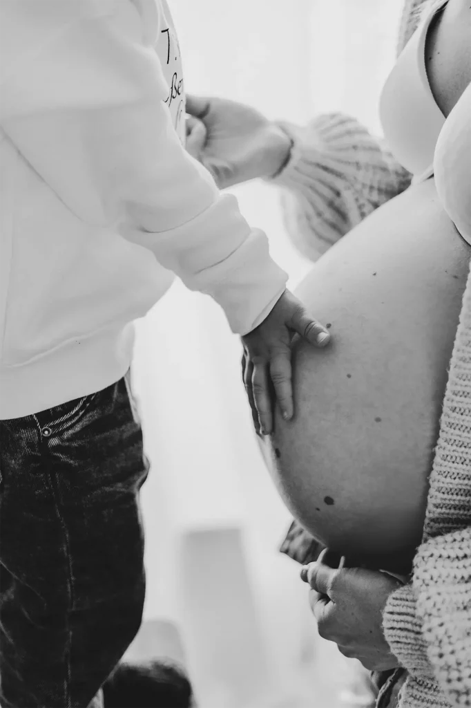 Ein Kind fasst an den schwangeren Bauch seiner Mutter fotografiert von Familienfotografin Katja Stumbeck